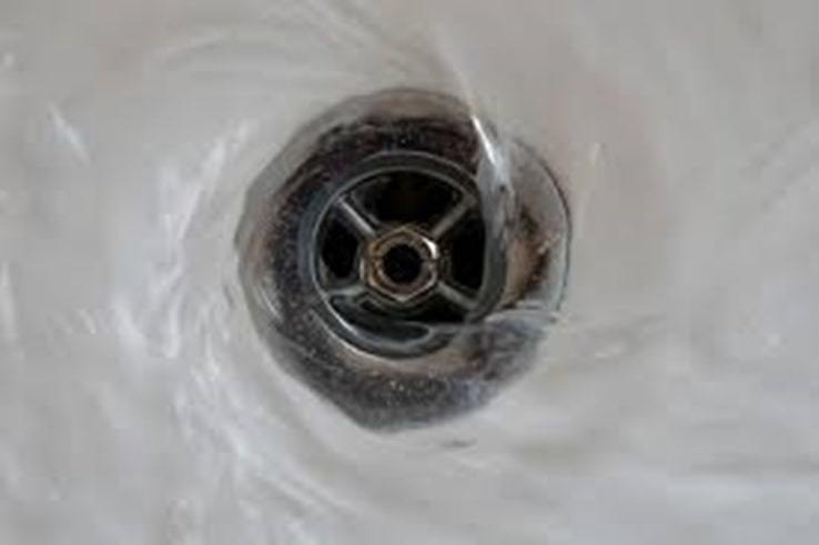 Closeup of water swirling down a drain.